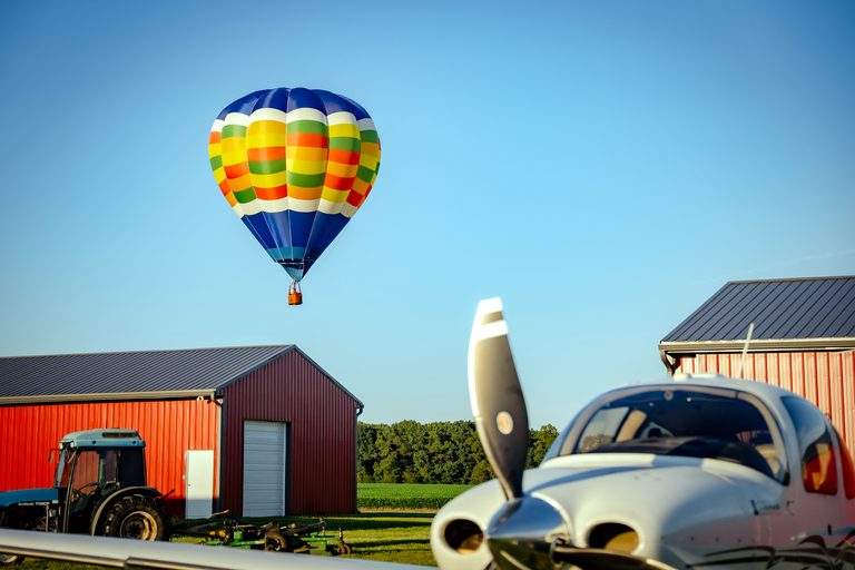 Hot air balloon over Bucks Airport with airplane in foreground
